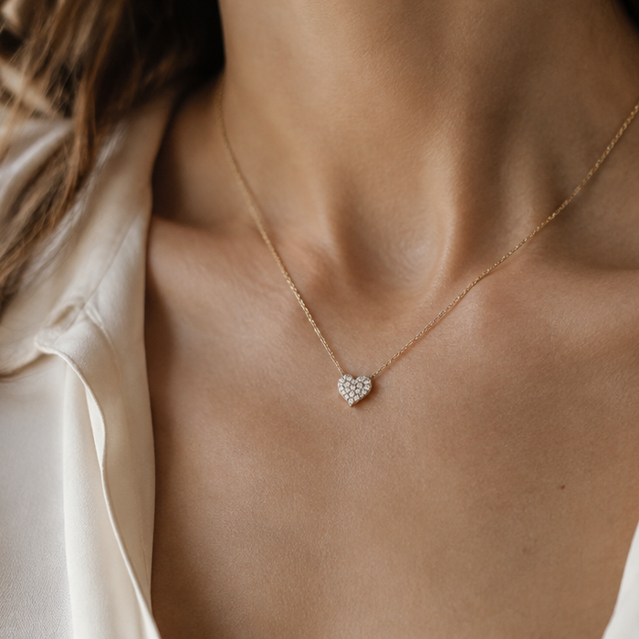 Diamond heart pendant on a fine gold chain resting below the collarbone