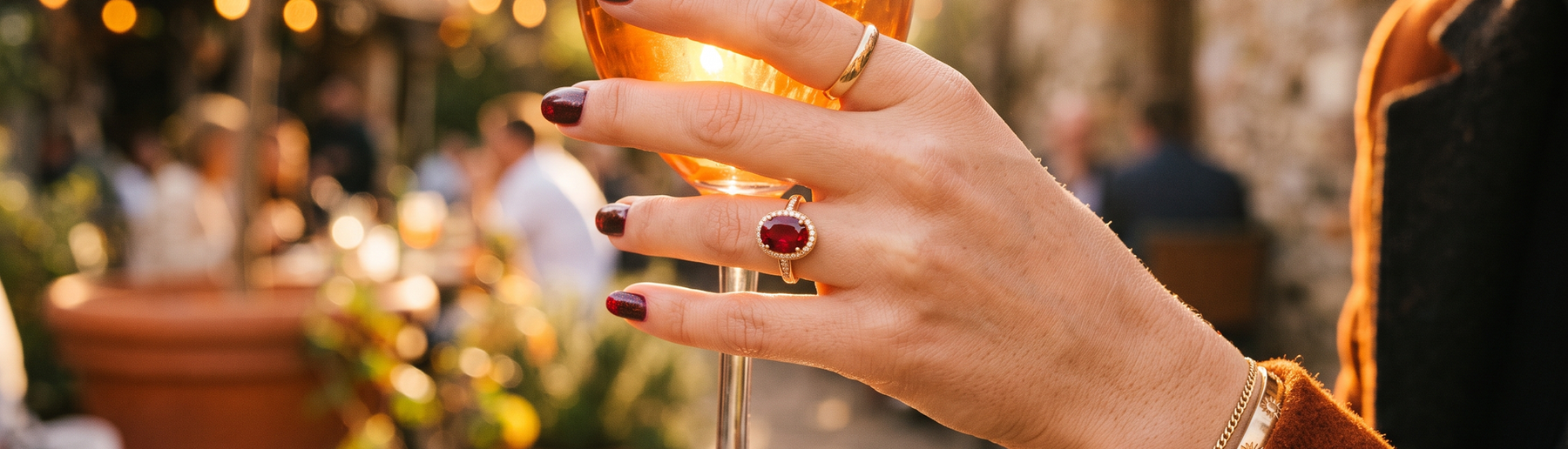 Hand wearing a ruby ring in warm golden-hour sunlight, editorial jewelry lifestyle photo
