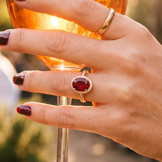 Hand wearing a ruby ring in warm golden-hour sunlight, editorial jewelry lifestyle photo