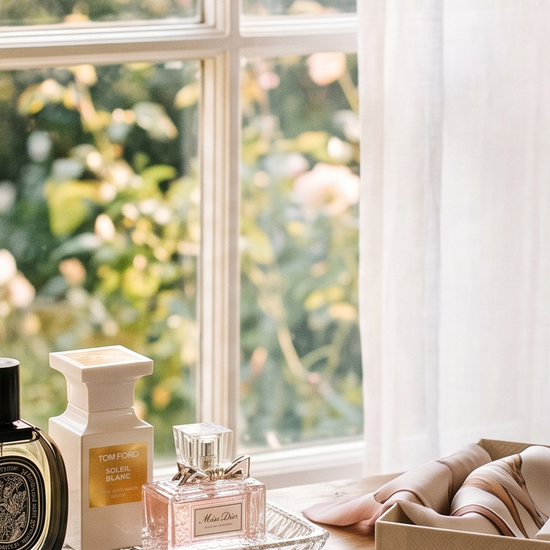 Vanity table with luxury perfume bottles and an open gift box in soft morning light
