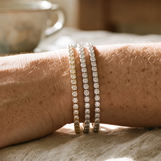 Woman's wrist wearing a stack of lab-grown diamond tennis bracelets in natural light