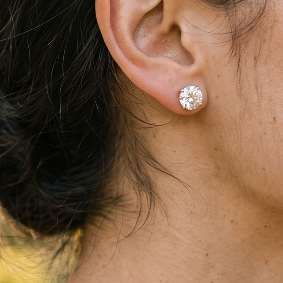 Woman's ear wearing lab-grown diamond stud earrings in natural light