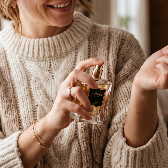 Person applying luxury winter fragrance near a window in cozy winter light