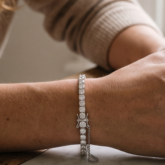 Woman wearing a lab-grown diamond tennis bracelet with a secure clasp, resting her wrist on a marble counter