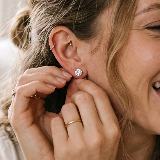 Woman putting on lab-grown diamond stud earrings