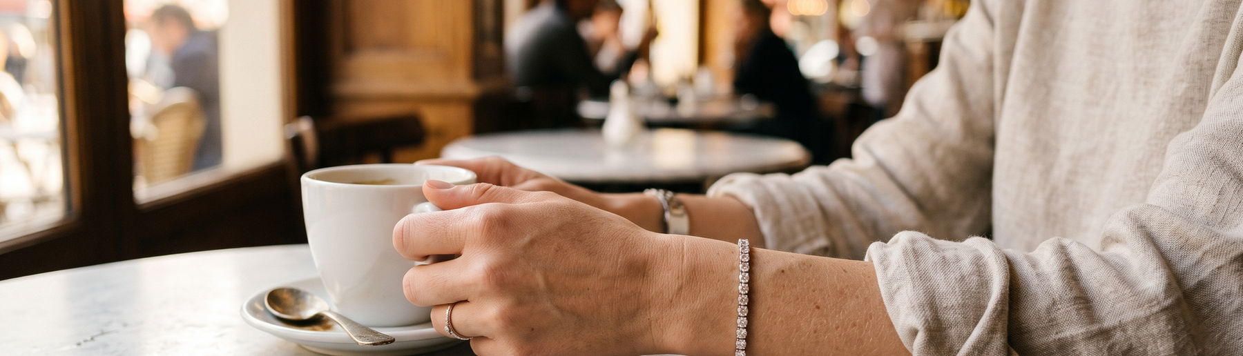Woman wearing a lab-grown diamond tennis bracelet at a cafe table in natural light