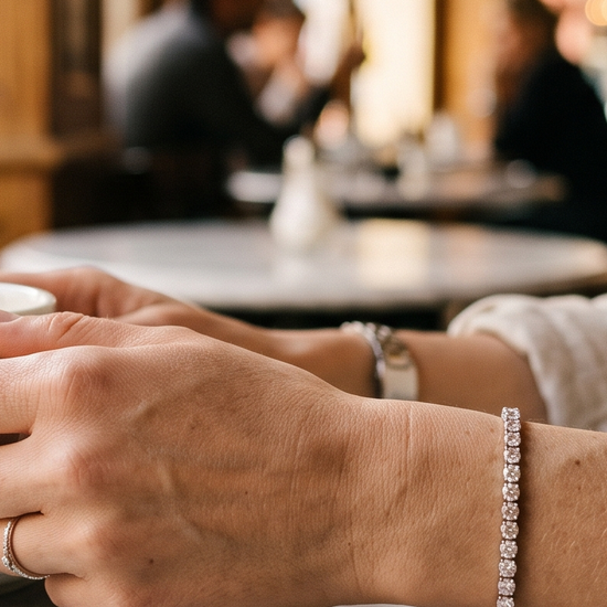 Woman wearing a lab-grown diamond tennis bracelet at a cafe table in natural light