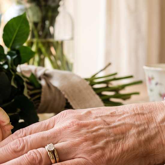 Woman's wrist wearing a lab-grown diamond tennis bracelet near a bouquet of flowers for Mother's Day