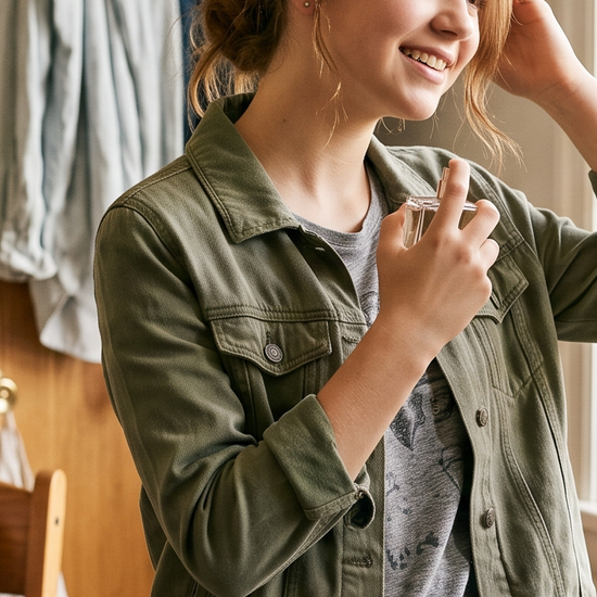 Teenage student spritzing perfume before heading to school in a sunlit bedroom