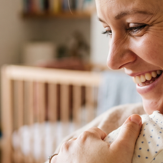 New mother holding her newborn baby, wearing a lab-grown diamond stud earring
