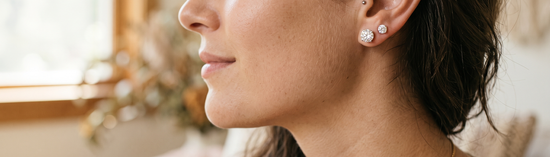Close-up of a woman's ear wearing lab-grown diamond stud earrings in natural light