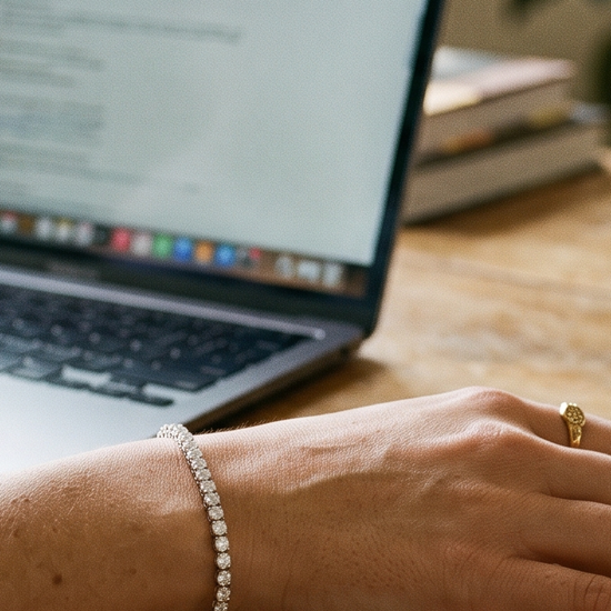Woman's wrist wearing a lab-grown diamond tennis bracelet at a desk in natural light