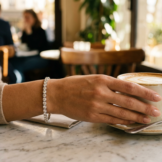 Woman wearing a lab-grown diamond tennis bracelet at a cafe table in natural light