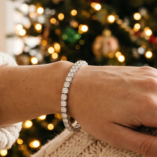 Woman's hand wearing a lab-grown diamond tennis bracelet near a Christmas tree