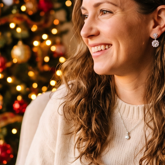 Woman wearing lab-grown diamond stud earrings near holiday lights
