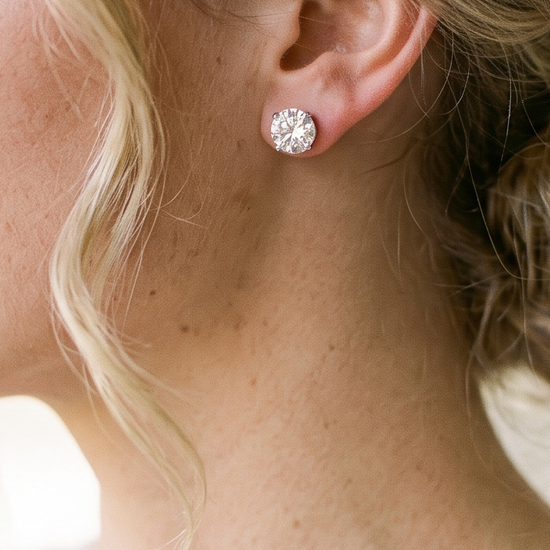 Close-up of a bride wearing a lab-grown diamond stud earring with a soft-focus veil in the background