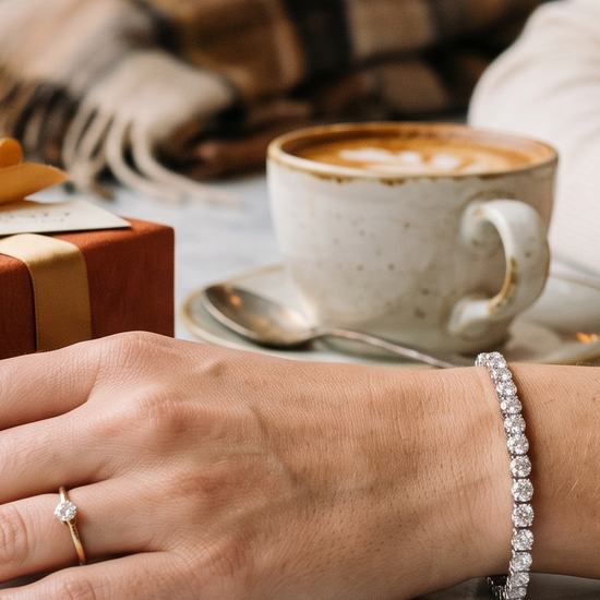 Woman's wrist wearing a lab-grown diamond tennis bracelet next to a wrapped gift box